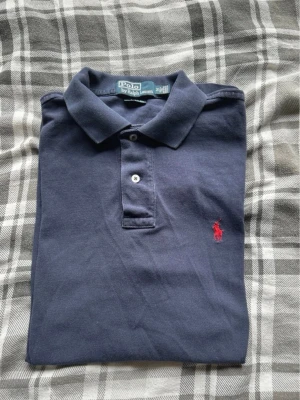 Polo Ralph Lauren Piké - | Polo Ralph Lauren | Custom Fit | Piké |Mörkblå | Röd Logga | Medium | Mycket Bra Skick |199kr |   Axelbredd: 42cm  Längd: 67cm  Skickas inom 24h📦  Kontakta vid minsta fråga eller fundering🤩 