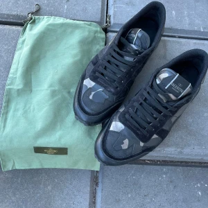 Valentino Rockrunners 44 - Säljer ett par Valentino Rockrunner sneakers med svart och grått camouflage-mönstersom är storlek 44 . Skorna är sparsamt använda och till skorna tillkommer även påse 