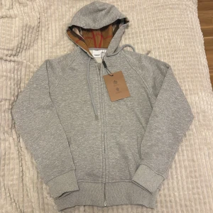 Grå hoodie från Burberry  - Kan diskutera pris, Säljer en stilren grå hoodie från Burberry med dragkedja storlek s passar xs och xxs 