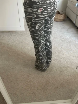 zebra jeans från Guess - Säljer ett par gråa jeans från Guess med vitt zebramönster. Jeansen har raka ben, normal midja och klassiska fem fickor. Snygg logga på bakfickan och coolt mönster som sticker ut. 