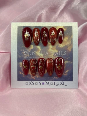 Glint (M);Medium Almond - Handgjorda press-on naglar i storlek M: 16 mm, 12 mm, 12,5 mm, 11,5 mm, 10 mm. Djup vinröd bas med skimrande cateye effekt och detaljerade guld- och rött motiv som hjärtan, stjärnor och mystiska symboler. Medium längd, mandelformade naglar, för en unik och konstnärlig look.