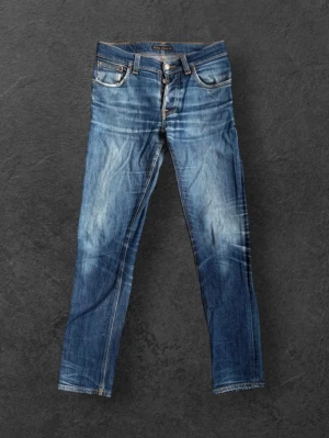 Nudie Jeans Grim Tim Dry Open Navy - W31 L34 - Nudie Jeans Grim Tim Dry Open Navy - W31 L34.  Bra skick. Fina naturlig patina. Skrev lagat hos Nudie Jeans i Göteborg. Hål i båda fickorna samt pyttelitet hål på insidan vänsterbenet mot sömmen. Se bilder. Enkelt att lösa genom att lämna in på Nudie Jeans för gratis lagning.  98% bomull 2% stretch  Se bilder för skick, kontakta mig gärna för frågor.  Midja 39 cm Längd 104 cm Innerbenslängd 80 cm
