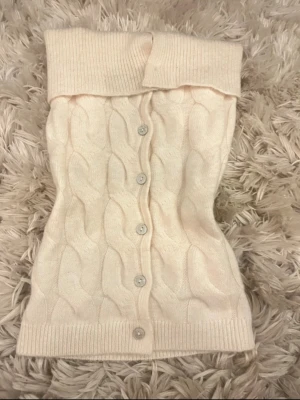 Stickad tubtröja - Säljer en beige kabelstickad tubtröja med knappar framtill och bred ribbad kant upptill och nedtill🥰