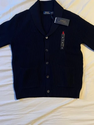 Marinblå Cardigan från Polo Ralph Lauren - Säljer en marinblå ribbstickad cardigan från Polo Ralph Lauren i storlek M men passar S fint. Perfekt för vintern och kyligare dagar! Nypris: 4999kr, Mitt pris: 1999kr / Skriv vid frågor 😊🤝