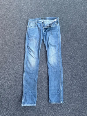 Blå slim fit jeans från Replay - Snygga blå slim fit jeans från Replay med klassisk femficksdesign och dragkedjegylf. Jeansen har en lätt tvättad look med slitningar på låren och raka ben. Perfekta för en avslappnad och trendig stil.          Storlek 30-34