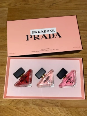 Prada Paradoxe parfymset 3x30ml - Exklusivt parfymset från Prada med tre olika dofter ur Paradoxe-serien. Flaskorna är trekantiga i glas med svarta lock och rosa, ljusrosa och orange toner. Lyxig förpackning i rosa med svart text. Varje flaska innehåller 30 ml Eau de Parfum och är påfyllningsbar.