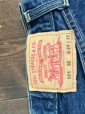 Levi's 521 raka blå jeans W29 L32 - Klassiska blå Levi's 521 jeans med rak passform och normal midja. Jeansen har fem fickor, gylf med dragkedja och är tillverkade i slitstark denim. Perfekta för en avslappnad och tidlös stil. Priset står inte skrivet i sten!