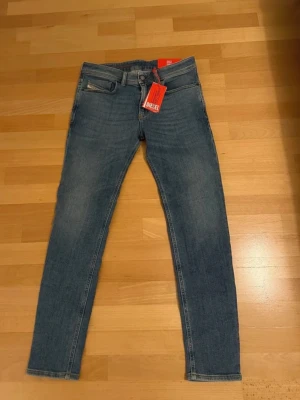 Blå slim fit jeans från Diesel, HELT NYA - !!HELT NYA!! Snygga blå slim fit jeans från Diesel med klassisk femficksdesign och diskreta slitningar. Jeansen har normal midja, smala ben och är tillverkade i stretchigt denim för extra komfort. Perfekta för en trendig och avslappnad stil.