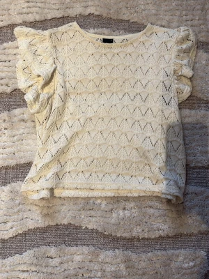 Beige spetsblus🥰 - Supersöt beige blus med spetsdetaljer och puffiga korta ärmar. Mönstret är genombrutet och ger en romantisk vibe. Perfekt att styla med jeans eller kjol för en trendig look. Ganska liten i storleken!