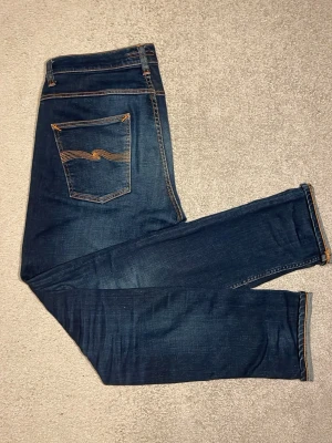 Mörkblå Nudie jeans - Säljer ett par mörkblåa Nudie jeans med en asnajs tvätt och riktigt go passform i modellen Grim Tim och storleken 33/34. Jeans är i toppskick utan några skavanker. Skriv vid eventuella frågor🙋