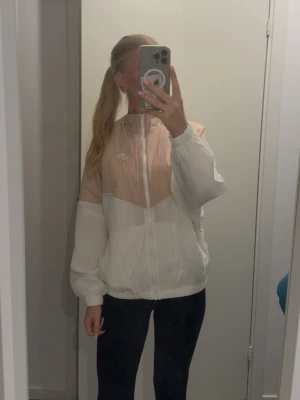 Nike träningsjacka i rosa och vitt storlek S - Snygg träningsjacka från Nike i rosa och vitt, den är mer rosa i verkligheten! Jackan har dragkedja, elastiska muddar och logotyp på bröstet. Jackan är i mycket bra skick och storlek S