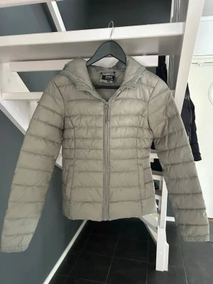 Ljus grön pufferjacka från ONLY - Snygg ljus grön pufferjacka från ONLY med huva och dragkedja framtill. Jackan har quiltad design och raka ärmar. Perfekt för kalla dagar och enkel att matcha med olika outfits. Tillverkad i lätt och värmande material. Använd max 3 gånger
