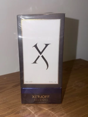 Xerjoff Accento Eau de Parfum - Säljer en lyxig parfym från Xerjoff, Accento Eau de Parfum. Flaskan är 100 ml och kommer i en elegant förpackning med svart och vit design samt guldfärgade detaljer. Perfekt för dig som vill ha en exklusiv doftupplevelse.