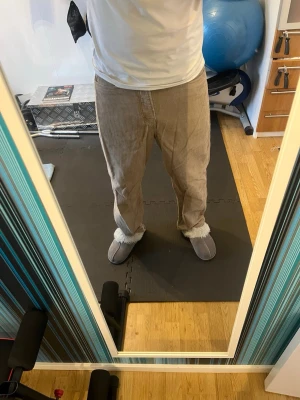 Beige manchesterbyxor med raka ben - Säljer ett par beige manchesterbyxor med klassisk femficksmodell och raka ben. Byxorna har breda revärer och stängs med knapp och dragkedja. Perfekta för dig som gillar retrostil och vill ha något bekvämt och snyggt i garderoben.