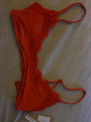 Röd spetsbralette från Skims - Trendig röd bralette från Skims med tunna axelband och dekorativa spetsdetaljer längs kanterna. Modellen är en scoop bralette i färgen 'Cayenne', perfekt för dig som gillar bekväma och snygga underkläder med en feminin touch.