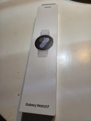 Samsung Galaxy Watch7 smartklocka vit - Samsung Galaxy Watch7 med rund svart urtavla och vit silikonrem. Modern design med touchskärm och justerbart armband. Perfekt för dig som vill ha koll på hälsa, träning och notiser direkt på handleden. Kommer i originalförpackning.