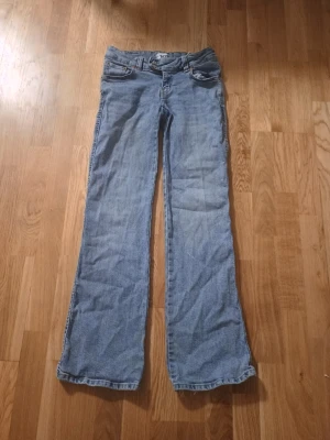Ljusblå bootcut jeans från 157 - Ljusblå jeans med bootcut-modell från 157. Klassisk femficksdesign, dubbla knappar i midjan och bälteshällor. Jeansen har en avslappnad passform och är tillverkade i denim. Perfekta för en casual look.
