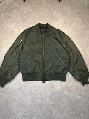 GU X Undercover Bomber Jacket - 📏 Size: S Fits true to size Cropped, boxy fit  ♻️ Condition: 9/10 No signs of wear Listed as 9/10, because 10/10 would be brand new with tags  🧵 Outer material: 100% nylon  📸 Details: Overly long zipper, branded hardware, sleeve tag, print on the back