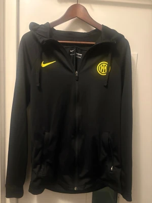 Svart Inter zip hoodie - Svart hoodie från Nike med Inter Milan-logga. Skön och snygg tröja säljs. Storlek M men skulle också passa vissa S. Nästan helt ny använd få gånger. Hör av intresse!☺️