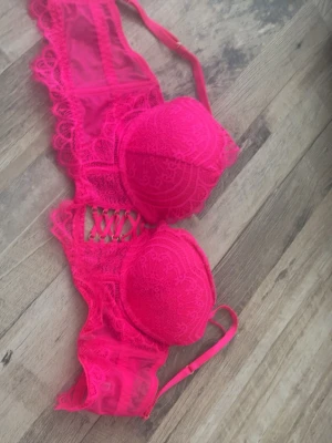 Rosa spets-bh med snörning - Snygg rosa bh med vadderade kupor och dekorativ snörning framtill. Bh:n har spetsdetaljer och justerbara axelband för bästa passform. Materialet är en kombination av spets och mesh som ger en feminin och trendig look.