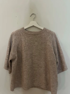 Beige stickad tröja med halvärm - Mysig beige stickad tröja med rund halsringning och halvlånga ärmar. 