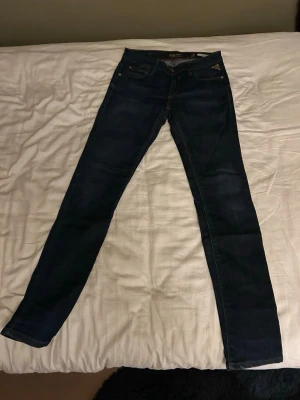 Mörkblå slim fit jeans från Replay - Säljer ett par mörkblå skinny jeans från Replay, modell Rockxan. Jeansen har klassisk femficksdesign, snygga kontrastsömmar och Replay-logga i metall på fickan. Perfekta för dig som gillar en slim passform och stilren look.