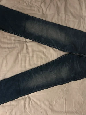 Blå jeans från polo Ralph lauren - Säljer ett par klassiska blå jeans från polo Ralph lauren med raka ben och snygga slitningar. Jeansen har fem fickor och en läderpatch bak i midjan. Materialet är denim och färgen är mörkblå med ljusa partier. Perfekt för dig som gillar en avslappnad och cool stil. Köptes på nk för 1800 förra året men säljer nu passar dig mellan 165-170 bäst