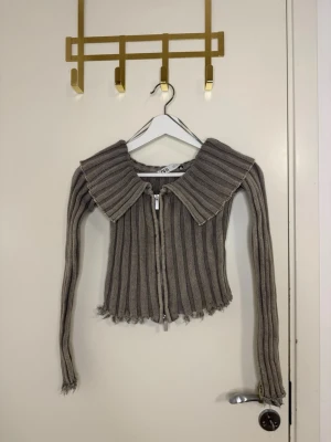 Grå ribbstickad ziptröja  - Tröjan är långarmad i storlek S  