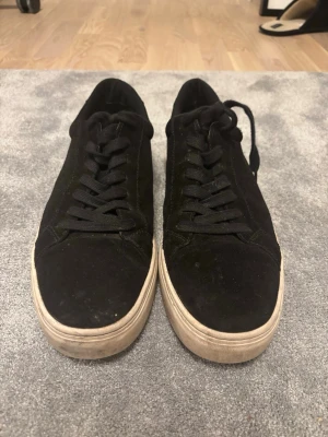 Svarta låga sneakers i mocka vagabond - Snygga svarta sneakers i mocka med vita sulor och svarta skosnören. Klassisk låg modell som passar till det mesta och ger en clean look. Perfekta för dig som gillar stilrena och enkla skor.