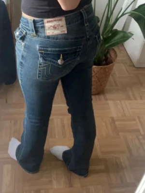True religion Becca mid rise flare jeans - Populära mörkblåa jeans med gula sömmar från true religion. De är i mid Rise men som du ser på bilderna så är de lågmidjade. De är väldigt varsamt andvända och har absolut inga skavanker alls.
