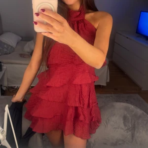 Röd volangklänning med halterneck - Supersöt röd kort klänning med flera volanglager och halterneck som även kan bäras axelbandslös. 