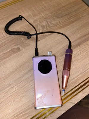 Rosa elektrisk nagelfil - Elektrisk nagelfil i metallic rosa med handtag och kontrollenhet. Perfekt för att forma och släta ut naglar, både naturliga och konstgjorda. Kommer med spiralformad sladd och justerbar hastighet. Smidig design som är enkel att använda hemma.