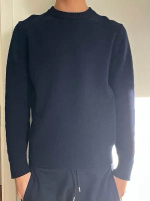 Tröja från massimodutti - En enkel och stilren mörkblå stickad tröja med rund hals och ribbade muddar vid ärmslut och nederkant. Tröjan har en rak passform och är perfekt för lager på lager. Materialet ser ut att vara mjukt och bekvämt, troligen ull eller bomull. Storlek L men har krympt i tvätten . Modellen på bilden är 176.🤩📦