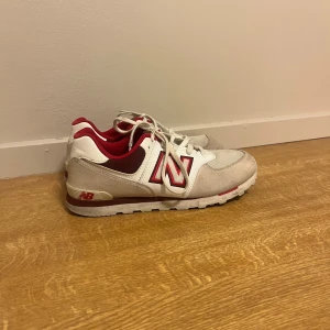 New Balance vita och röda sneakers - Snygga vita och röda sneakers från New Balance med klassisk N-logga på sidan. Skorna har mesh och mockadetaljer, vita snören och röd insida. Yttersulan är grå med röda detaljer. Perfekta för dig som gillar sportig och stilren look. Sparsamt använda då de är för små för mig❤️❤️ pris kan diskuteras