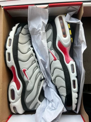 Nike Air Max Plus - Färg : Photon Dust/Particle Grey/Svart/Varsity Red   Säljer min killes Nike Air Max Plus då de är för små och därför knappt använda.  Använda max 5–6 gånger. Mycket fint skick & minimalt slitage på sula  Köpta direkt från Nike. Box medföljer (etikett borttagen).  Nypris 1 899 kr. Seriösa bud välkomnas. 