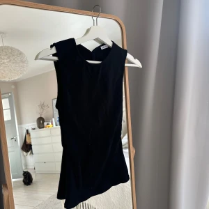 Svart topp från Zara med öppen rygg - Snygg svart ärmlös topp från Zara med rund halsringning och figurnära passform. Toppen har en stilren design och är perfekt att matcha med både jeans och kjol. Öppen slitts i ryggen!! Sitter som en S men passar både S och M