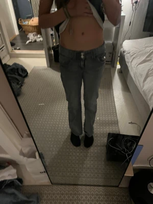 Blå raka jeans med låg midja - Säljer ett par klassiska blå jeans med rak passform och låg midja. Jeansen har fem fickor, bälteshällor och stängs med knapp och dragkedja. Perfekta till vardags och passar till det mesta. Materialet är denim i bomull.