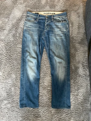 Denham Jeans  - Snygga blå jeans från Japansk märke Denham med slitna detaljer och tvättad look. Klassiska raka ben och normal midja. Snygga fades och storlek w29. 