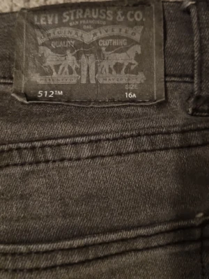 Svarta Levi's 512 jeans - Säljer ett par svarta Levi's 512 jeans med klassisk femficksdesign och raka ben. Jeansen har en snygg, mörk tvätt och är tillverkade i slitstarkt denim. Perfekta för dig som gillar en tidlös och stilren look. 