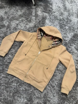 Beige Burberry kofta - Säljer min burberry kofta då den har blivit liten på mig. Det finns lite tecken på användning men inga skador på koftan. Färgen e speciell och är garanterat på att man sticker ut från mängden med denna färg. 