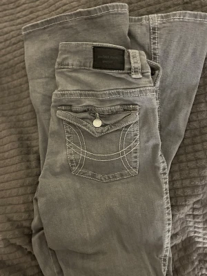 Grå jeans med knappfickor. - Super fina grå jeans som är bootcut och lågmidjade. Passar M.Pris kan diskuteras!!