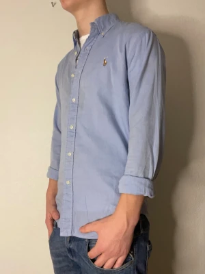 Ljusblå skjorta från Ralph Lauren - Ijusblå Ralph lauren skjorta i ett lite tunnare material. Modellen på bilden är 178 och väger cirka 70kg. Hör gärna av er ifall ni har frågor eller funderingar om varan!