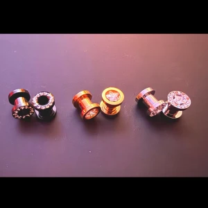Helt nya Örhängen, Tunnlar 6mm  - 6mm ståltunnlar.   2st svarta med limmade stenar.   2st guld med stjärna   2st silver med stjärna och stenar   Helt nya! Aldrig använda.   Säljer pga jag köpte fel storlek och tog ut dom ut förpackningen innan jag såg det. Så kunde inte returnera dom.  Köpa på piercingkungen  