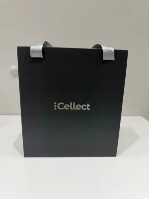 Cellect elektronik-kit presentbox - Snygg presentbox från Cellect fylld med olika elektronikprylar. Innehåller laddare, USB-kabel, kortläsare, ringhållare, trådlösa hörlurar och en blå powerbank. Allt ligger i en svart box med silverfärgade detaljer och handtag.