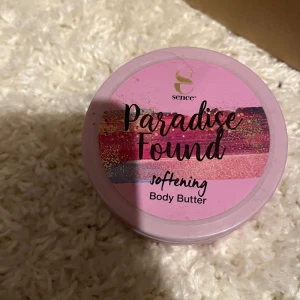 Paradise Found Body Butter Sence - Paradise Found softening body butter från Sence i en rund, rosa plastburk med färgglad etikett. Krämen är ljusrosa och har en krämig konsistens, perfekt för att återfukta huden och ge en mjuk känsla.
