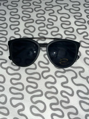 Svarta rektangulära solglasögon - Stilrena svarta solglasögon med rektangulära bågar och mörka glas. Perfekta för dig som gillar en minimalistisk och modern look. Passar till de flesta outfits och ger en cool vibe.