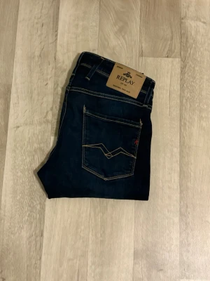 Mörkblå jeans från Replay - Snygga mörkblå jeans från Replay med klassisk femficksdesign och kontrastsömmar. Jeansen har raka ben och bakfickor med dekorativa sömmar. Perfekta för dig som gillar stilrena och tidlösa jeans.