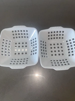 Två vita plastkorgar - Säljer två fyrkantiga vita plastkorgar med rutmönstrade sidor och handtag på kortsidorna. Perfekta för förvaring av småsaker, till exempel i köket, badrummet eller på skrivbordet.