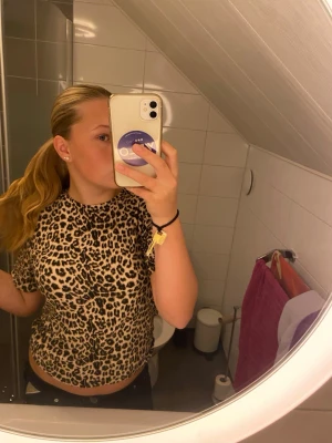Leopardmönstrad t-shirt - Cool t-shirt med leopardmönster i beige, brunt och svart. Modellen är kortärmad och har en klassisk rund halsringning. Perfekt för dig som vill sticka ut med ett djurmönster i din outfit.