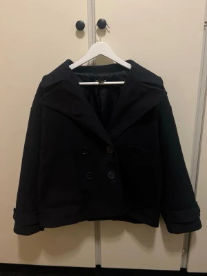Svart kort kappa med breda slag - Säljer en mörblå kappa från DesignBySi! Den är jättefin men lappen hänger på sniskan…  i strl XS/S men säljer eftersom den nu har blivit lite liten för mig💗